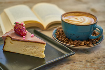 Latte coffee, coffee beans, cheesecake and book