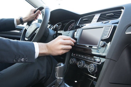 Business Mann bedient Autoradio in Mittelkonsole von Mittelklasse-PKW