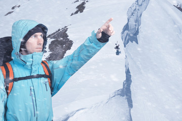 Portrait of adventurous young man on winter mountainside view pointing out. Active lifestyle and...