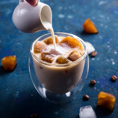 Cold summer refreshing drink with coffee ice and milk on a blue table