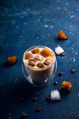 Cold summer refreshing drink with coffee ice and milk on a blue table