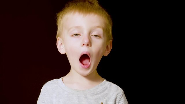 Motion studio portrait of an adorable little blonde boy acting speechless and amazed