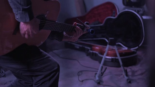 Musician stands up with guitar on stage slow motion dramatic close up