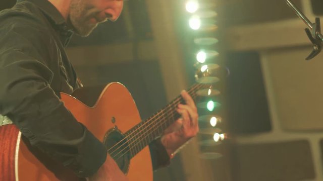 Musician playing guitar on stage slow motion tilt up.