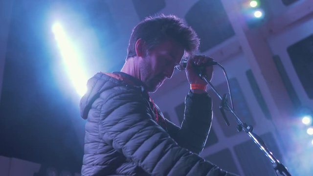 Musician on stage adjusting microphone
