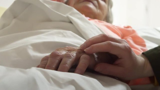 Caring for old grandmother bedridden with a cannula, close up shot