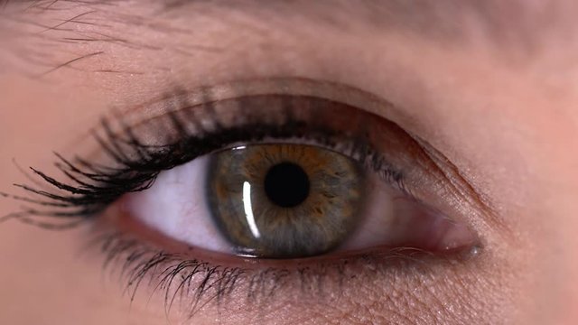 Close-up shot of woman opening her green eyes and focusing her sight.