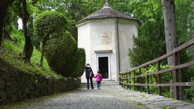 A mother and her little daughter carrying a teddy bear visiting the sacred mountain of Varallo christian devotional complex, a unesco world heritage site near the town of Varallo Sesia in Italy
