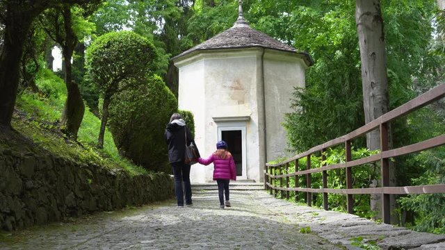 A mother and her little daughter carrying a teddy bear visiting the sacred mountain of Varallo christian devotional complex, a unesco world heritage site near the town of Varallo Sesia in Italy