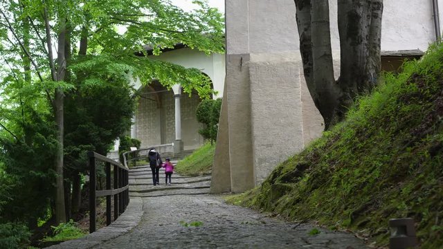 A mother and her little daughter carrying a teddy bear visiting the sacred mountain of Varallo christian devotional complex, a unesco world heritage site near the town of Varallo Sesia in Italy