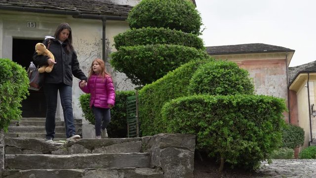 A mother and her little daughter carrying a teddy bear visiting the sacred mountain of Varallo christian devotional complex, a unesco world heritage site near the town of Varallo Sesia in Italy