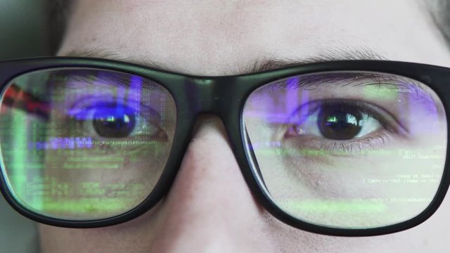 Green coding or hacking text is reflecting in the glasses static shot