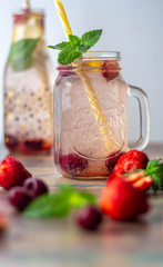 Fresh strawberries, mint and lemon cocktail on the background of a glass bottle with a drink. In the foreground fruit. White background.
