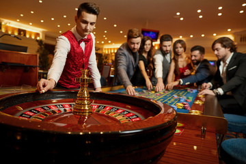 The croupier holds a roulette ball in a casino in his hand.