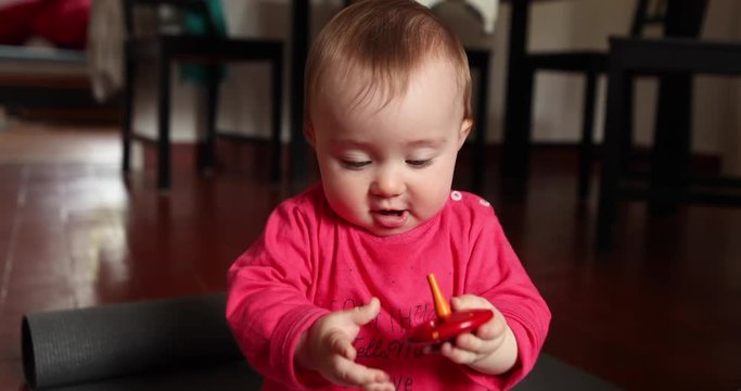 Happy cute little baby plays in front of the camera with a wood toy, shot in slow motion