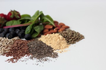 Sample foods from low-GI PCOS (Polycystic Ovary Syndrome) diet. Lentils, almonds, chia seeds, sunflower seeds, flaxseed, maca powder, blueberries, strawberries and dark leafy greens.	