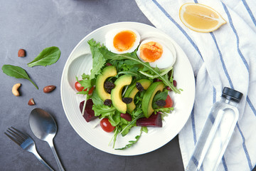Fresh healthy vegetable salad with egg, tomato, avocado, spinach, lettuce in plate on table background.
