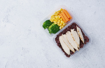 Fresh healthy diet lunch box with broccoli, carrot; corn and chicken on table background.
