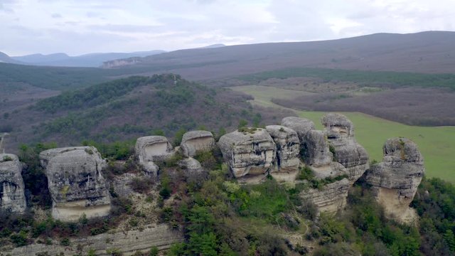 Flying over a natural impregnable mountain canyon. Ancient city fortress in rock. Historic cave town above high cliff. Dwelling in rocks. Tourist concept. Mountain landscape view