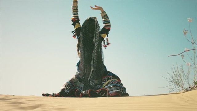 Gypsy woman smiling and waving her hands on a desert sand dune