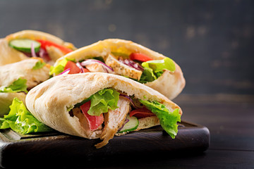 Pita stuffed with chicken, tomato and lettuce on wooden background. Middle Eastern cuisine.