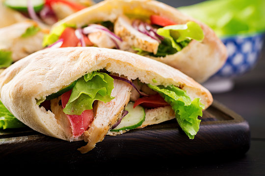 Pita stuffed with chicken, tomato and lettuce on wooden background. Middle Eastern cuisine.