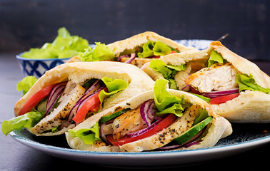 Pita stuffed with chicken, tomato and lettuce on wooden background. Middle Eastern cuisine.