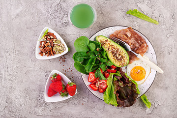 Plate with a keto diet food. Fried egg, bacon, avocado, arugula and strawberries. Keto breakfast. Top view