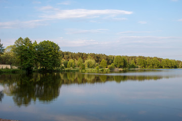 Landscape of a beautiful superficial blue lake surrounded by forest in the central part of Poland on a sunny summer day.