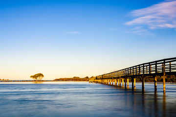 Wooden boardwalk over the sea in Urunga, New South Wales, Australia. Long exposure landscape at sunrise. 