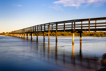 Obraz premium Wooden boardwalk over the sea in Urunga, New South Wales, Australia. Long exposure landscape at sunrise. 