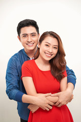 Portrait of a young couple hugging and standing against white background