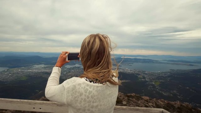 Women take a photo of the landscape in Tasamania, Australia.