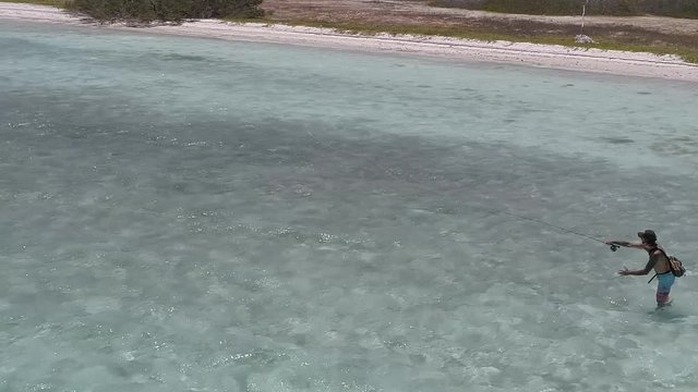 fly fisherman Casting at bonefish in turquoise-waters-in-the-Caribbean-sea-Los-roques-National-Park-Venezuela.