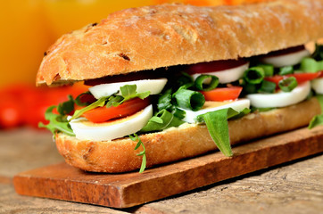 Baguette sandwich with egg, arugula salad, tomatoes and radish