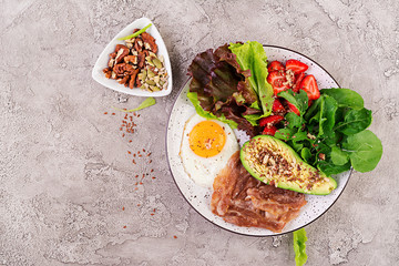 Plate with a keto diet food. Fried egg, bacon, avocado, arugula and strawberries. Keto breakfast. Top view