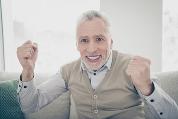 Close up photo amazing funky he him his aged man observe athletic match game achievement arms hands raised air wear white shirt waistcoat pants sit comfort bright flat house living room indoors
