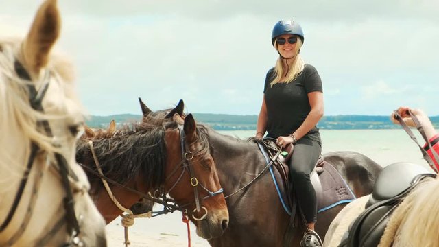 Slow motion shot of a blond woman smiling while sitting in a saddle on a horse at Bakers Beach Tasmania