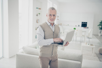 Close up side profile photo intelligent he him his aged man hands arms notebook search look information writing keyboard wear white shirt waistcoat pants sit cozy divan flat house living room indoors