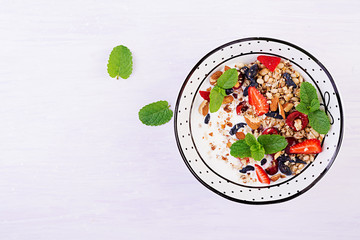 Healthy breakfast - granola, strawberries, cherry, honeysuckle berry, nuts and yogurt in a bowl....