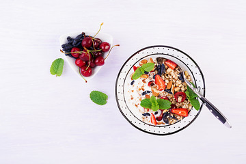 Healthy breakfast - granola, strawberries, cherry, honeysuckle berry, nuts and yogurt in a bowl....