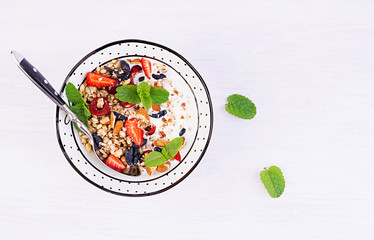 Healthy breakfast - granola, strawberries, cherry, honeysuckle berry, nuts and yogurt in a bowl....