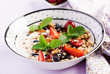 Healthy breakfast - granola, strawberries, cherry, honeysuckle berry, nuts and yogurt in a bowl. Vegetarian concept food.