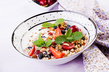 Healthy breakfast - granola, strawberries, cherry, honeysuckle berry, nuts and yogurt in a bowl. Vegetarian concept food.