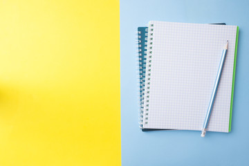 Clean white notebook and pencil with copy space on yellow blue table background for presentation, writer or school education, blogger, novel and friction or brand story concept.