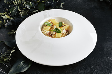 Exquisite Serving White Restaurant Plate of Risotto with Gorgonzola Cheese, Raisins, Almonds and Baked Pear Top View