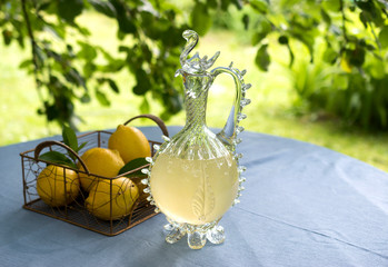 Homemade lemonade in a vintage carafe with lemons.