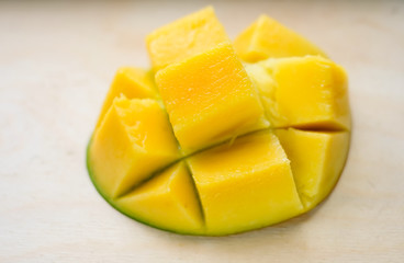 Ripe juicy yellow exotic mango cut into cubes on wooden background. Tropical delicacy full of vitamins for a healthy diet. Closeup. Selective focus.