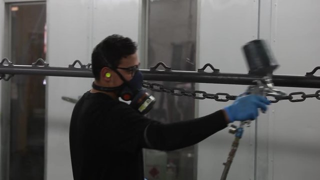 Professional air brusher working in a factory on metal parts 1