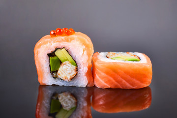 Philadelphia roll sushi with salmon, avocado, red caviar and cream cheese on black background for menu. Japanese food